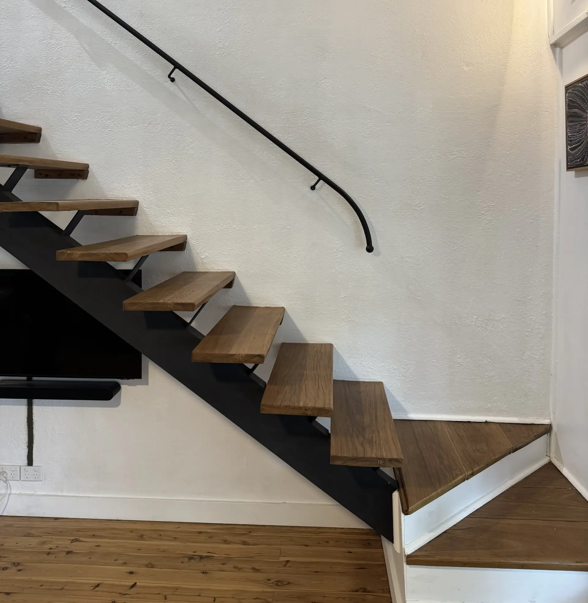 Black wrought iron handrail above a timber staircase, made by Anything Metal